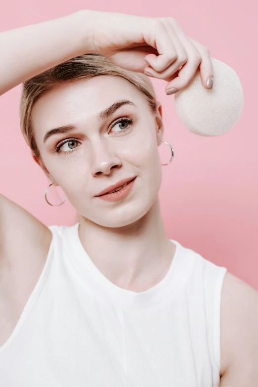 a young woman with frecks and earrings holding her hand up to the ear