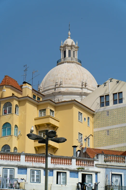 the building in front of the blue sky is a very large building with a white roof and a domed top