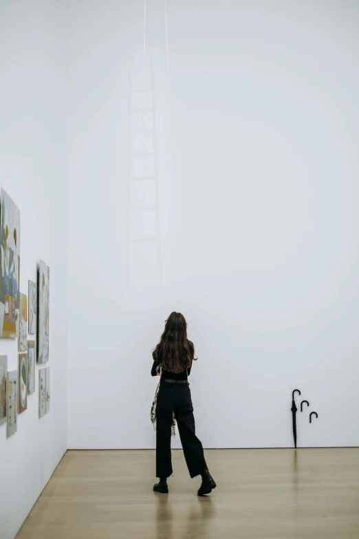 a woman walking through an art museum with pictures on the wall