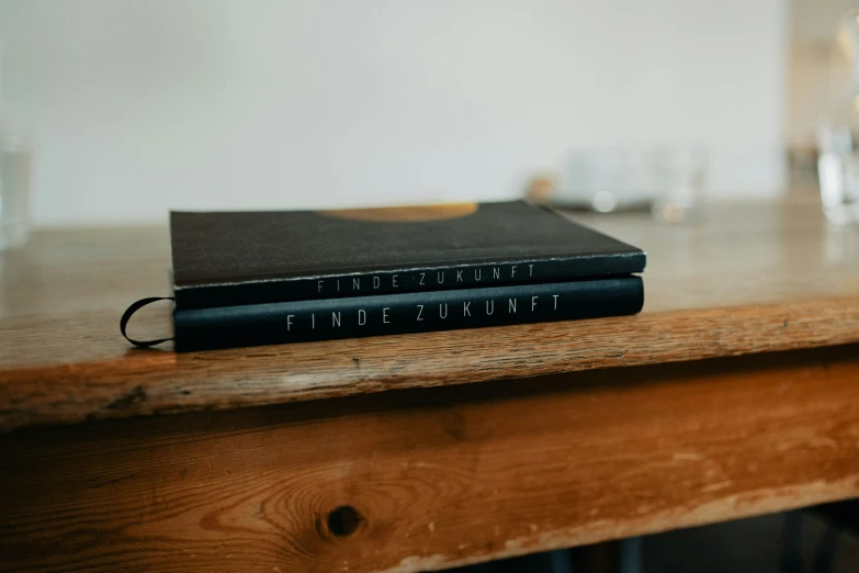 two black books sitting on top of a wooden table
