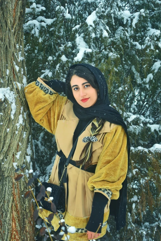 a woman posing in the snow holding onto a tree