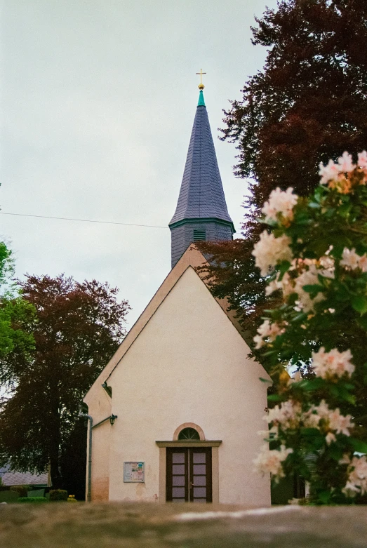 a small church with flowers in front of it