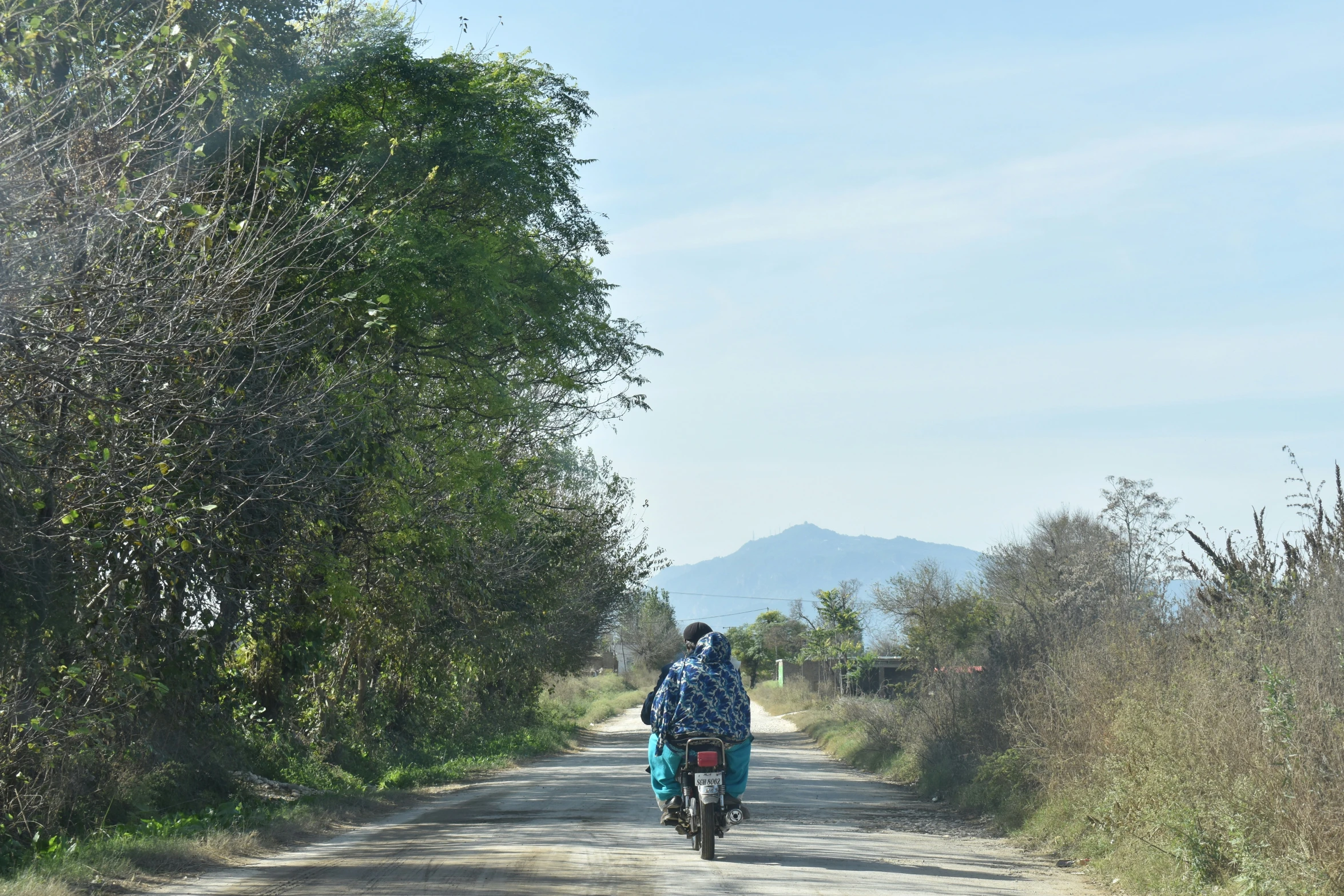 a man on a bicycle riding down the middle of a road