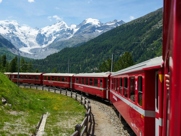 the train on the tracks near mountains is red