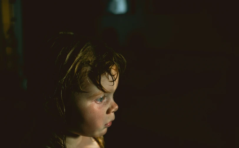 a little girl staring to the left in front of a dark background