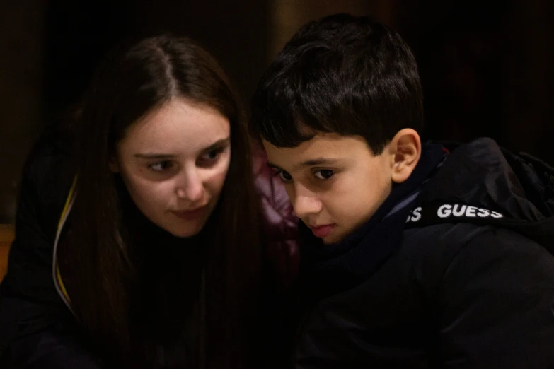 a girl and boy are looking at their phones