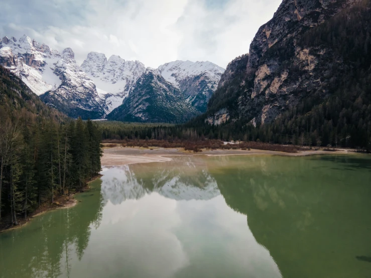 a mountain landscape with clear water and snow on the peaks