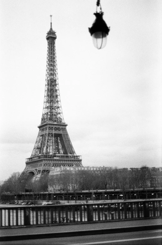 black and white pograph of a man looking at the eiffel tower in paris