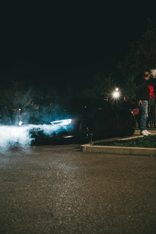 two people are standing near a black car on the street