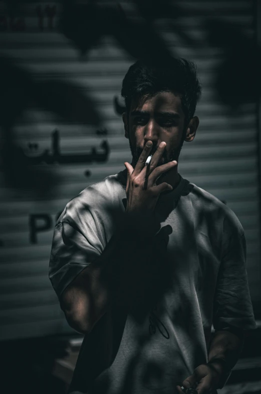 man smoking in a dark room with a metal wall