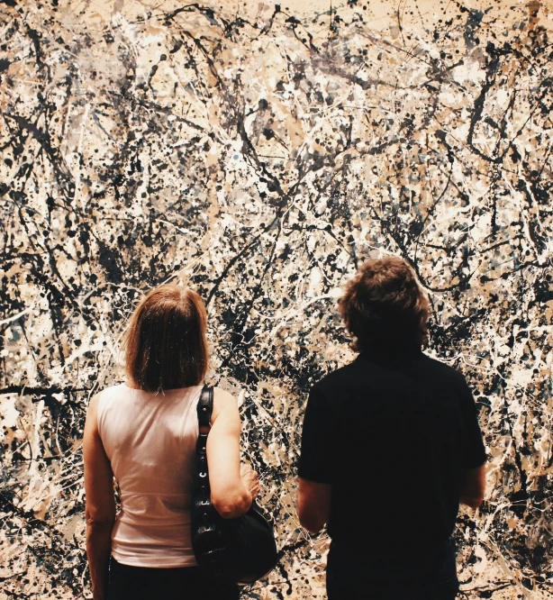 two people are standing in front of the wall