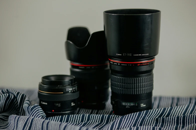 a cup, two lenses and one camera lens on top of the bed