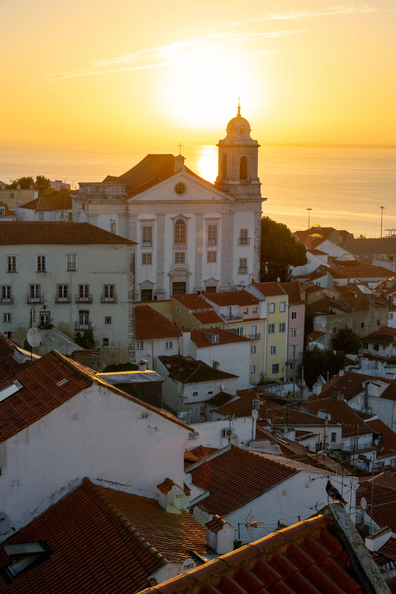 the sun is shining down over a city by the ocean