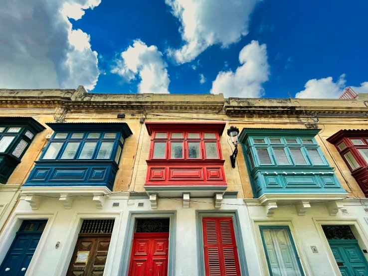 an upward po of many multi - colored windows with blue sky and clouds above