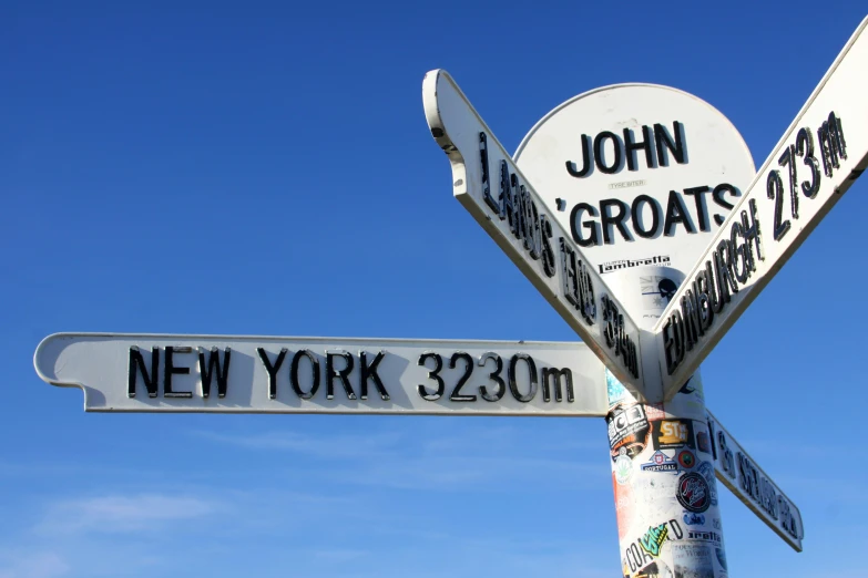 a close up of three street signs on a pole