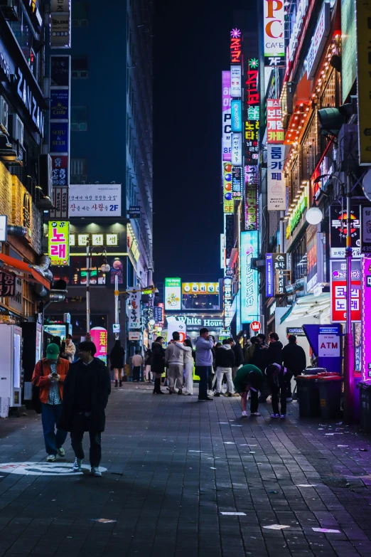 people are walking through a busy city at night