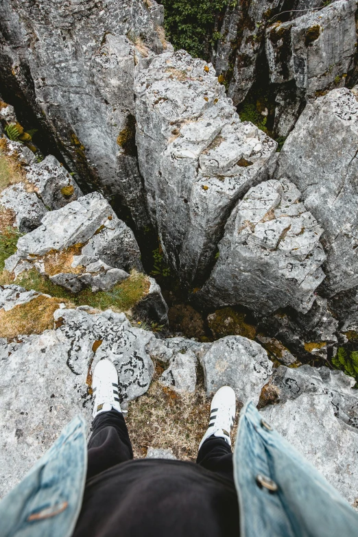 a view from a person's feet down on rocks and moss