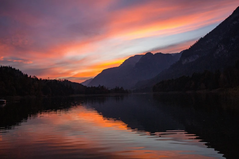 the sun rises over a mountain range and a body of water