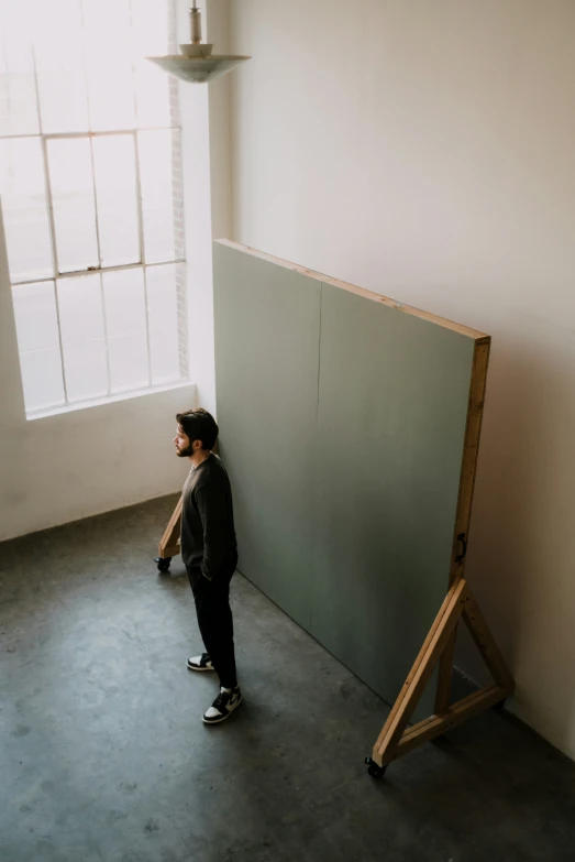 the man stands in front of a piece of furniture