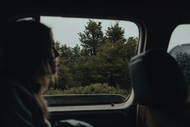 a woman riding on the back of a truck through trees