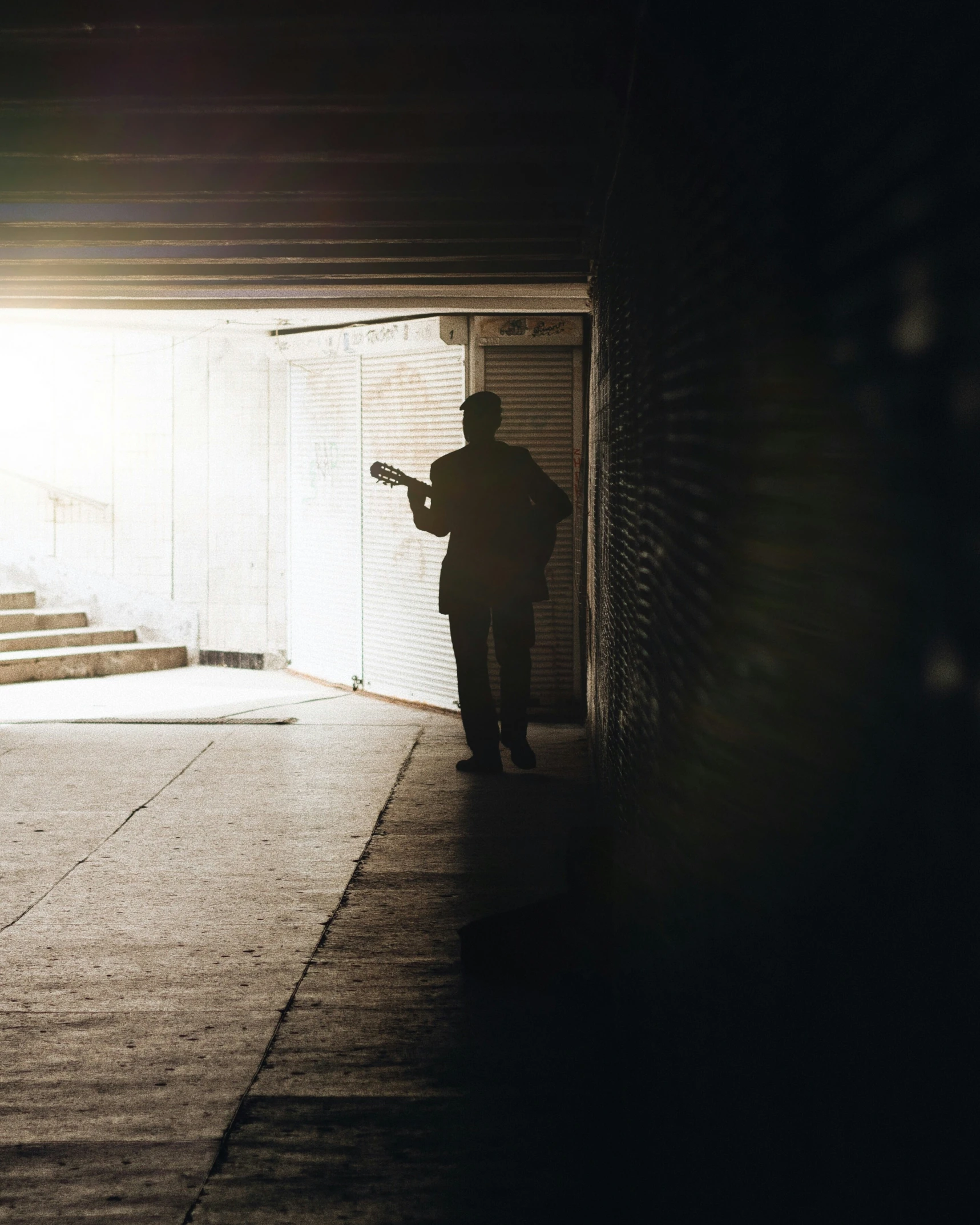 a person with an acoustic guitar stands in an open doorway