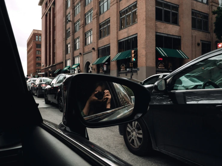 a lady takes a selfie in the rear view mirror