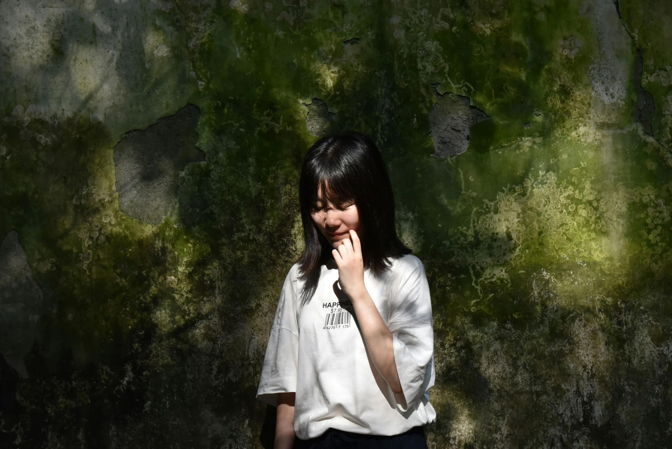 a woman standing in front of a wall covered in green grass