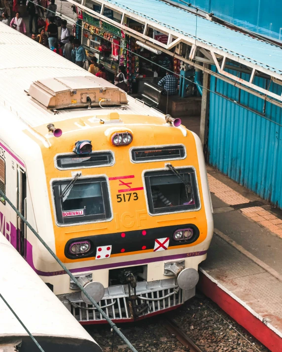 a yellow and white train stopped at a station