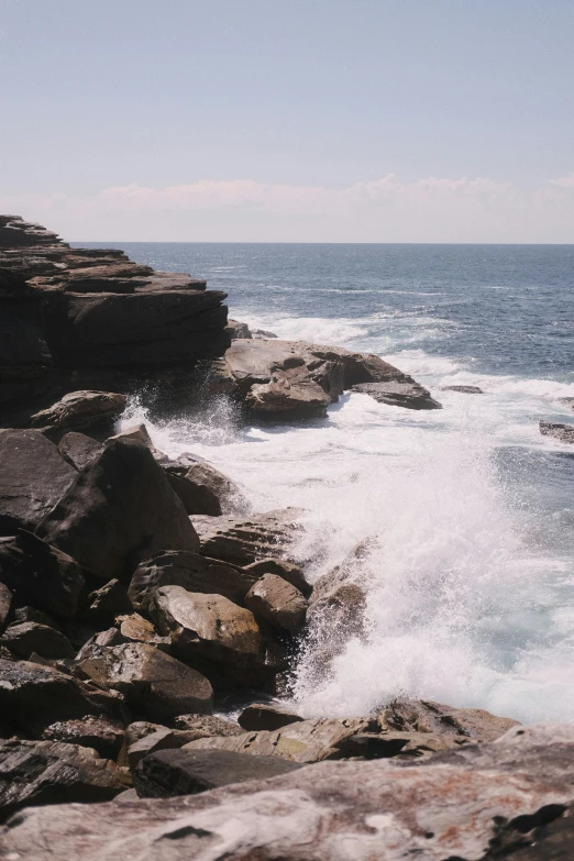 a couple on their surf board stand in front of some rocks