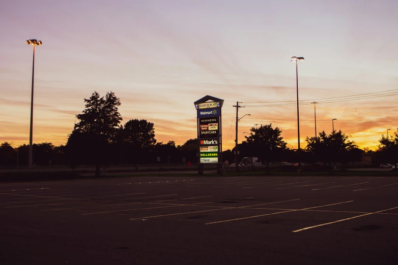 an empty parking lot at sunset with signs on it