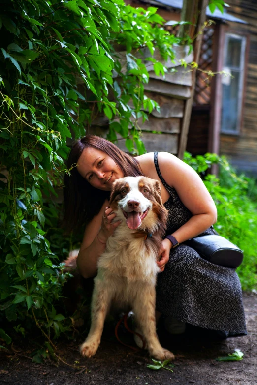 a woman with her dog posing in a garden