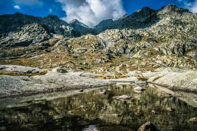 a large mountain with rocks and water near it