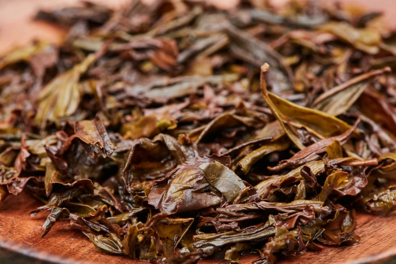 a wooden plate with brown leafy food on it