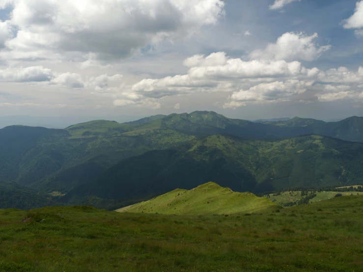 mountains covered in green grass with a mountain in the background