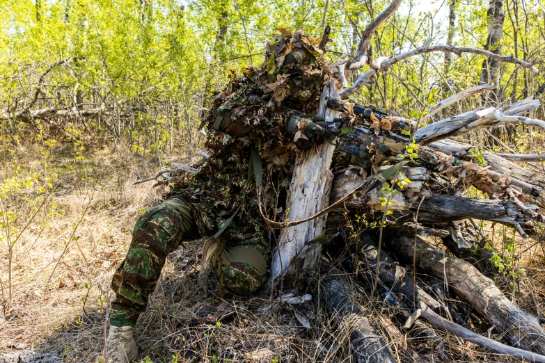 a man wearing camo is covered in foliage