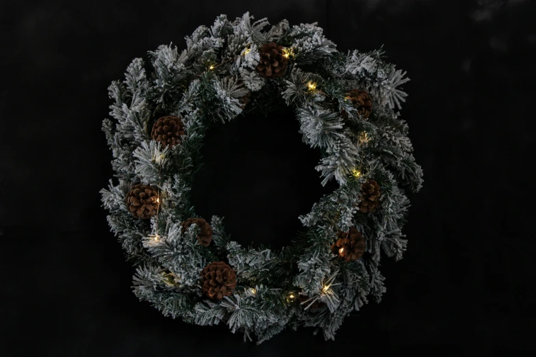 a christmas wreath with lights and pine cones