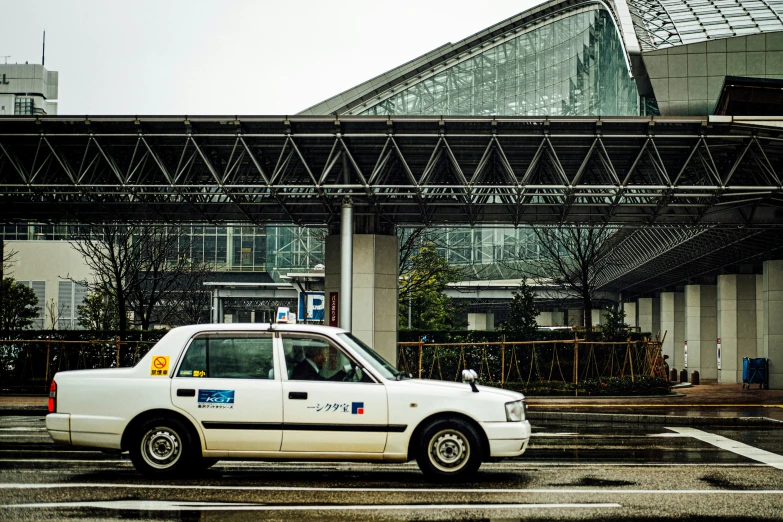 a white taxi parked by a building under a street bridge