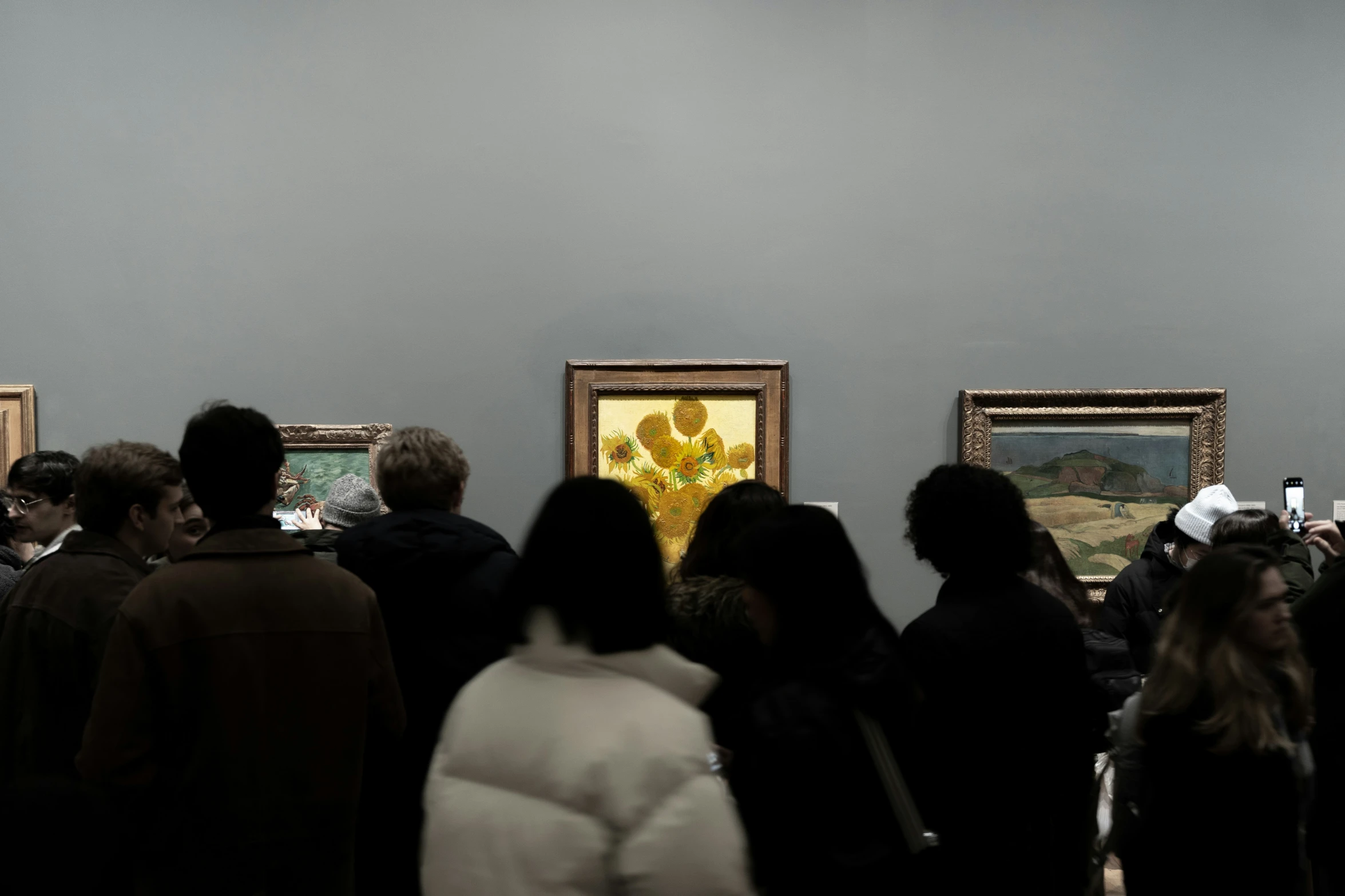 people looking at art in a museum with paintings on the wall