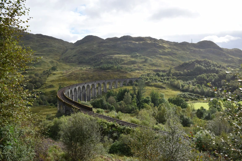 train tracks are in front of the bridge and mountains