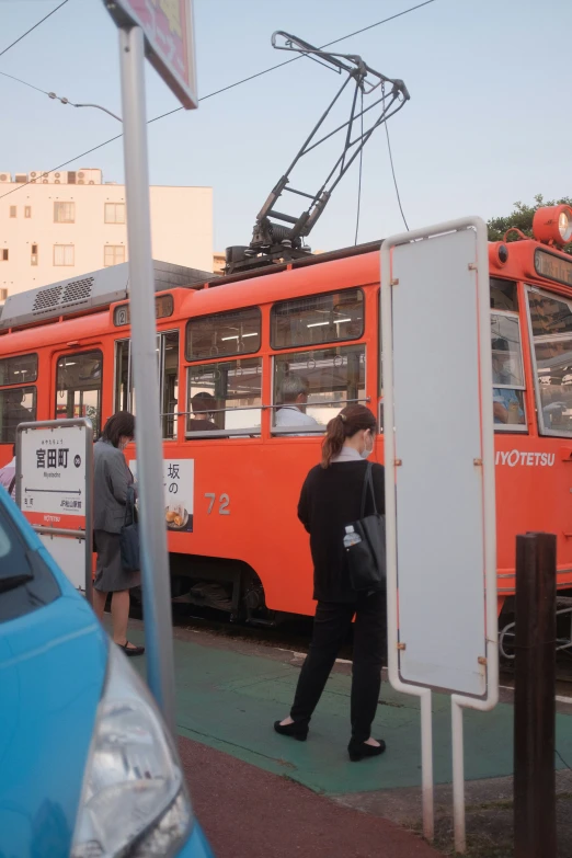 orange streetcar on the side of a street