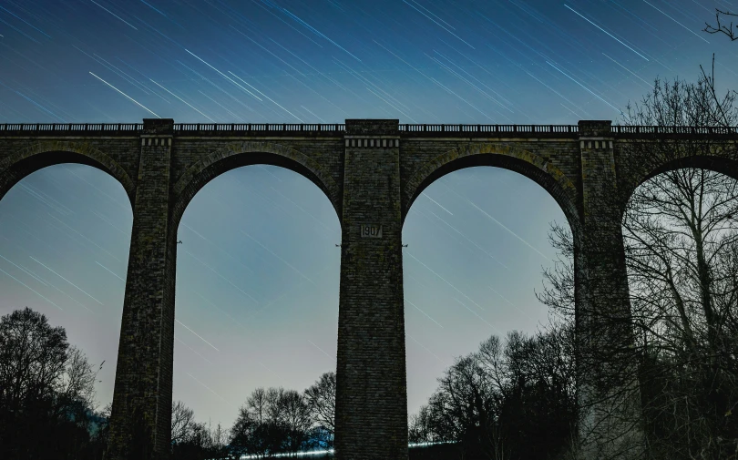 the train is traveling on the tracks by the bridge