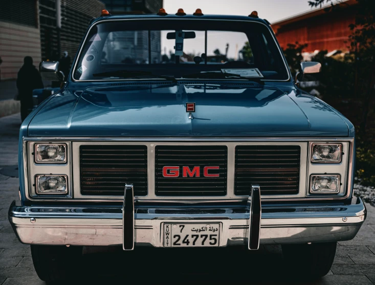 an older model blue gmc pickup truck sits in a driveway