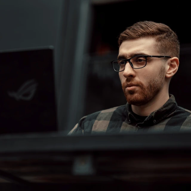 young man in glasses looking at his laptop screen