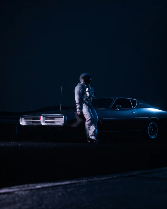 a man stands in front of his car at night
