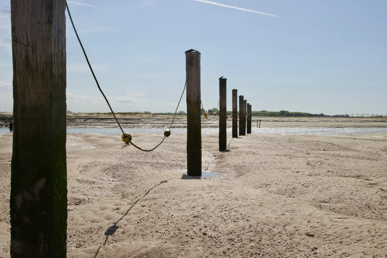 several wooden posts are on a sandy area