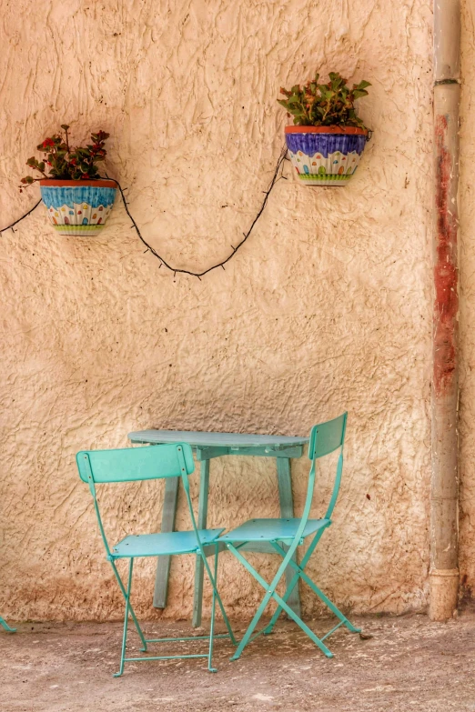 the front of an apartment building with two empty chairs and a small table