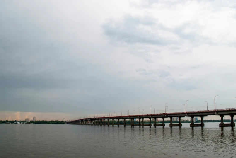 a long bridge over the water is shown under a cloudy sky