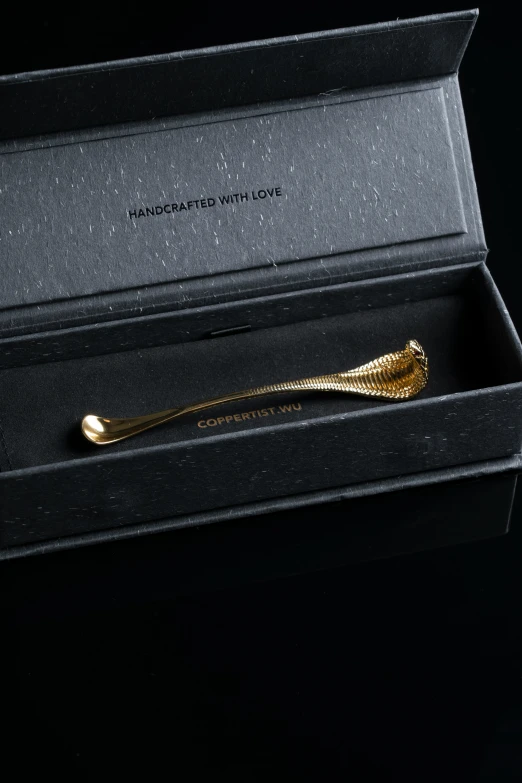 a gold tie clip in its box with writing on it