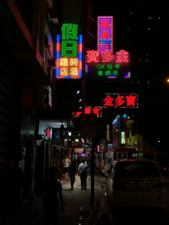 people are walking around the city with colorful neon signs