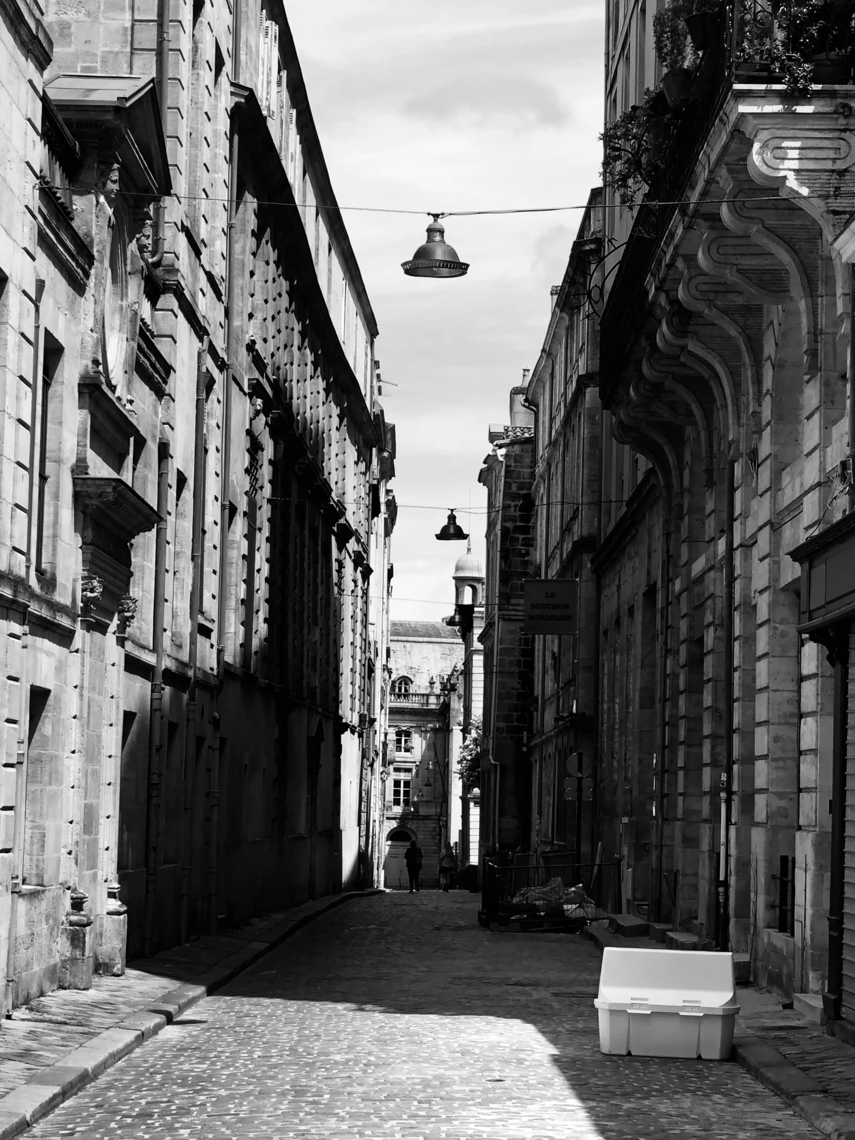 an empty city street with stone buildings and a bench